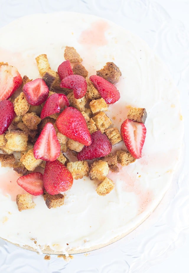 overhead image showing the top of a Strawberry Shortcake Cheesecake topped with sweet biscuit croutons and strawberry slices