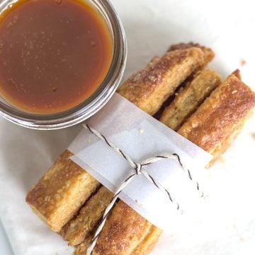 Cinnamon sticks with a flaky pie dipping sauce on a napkin.