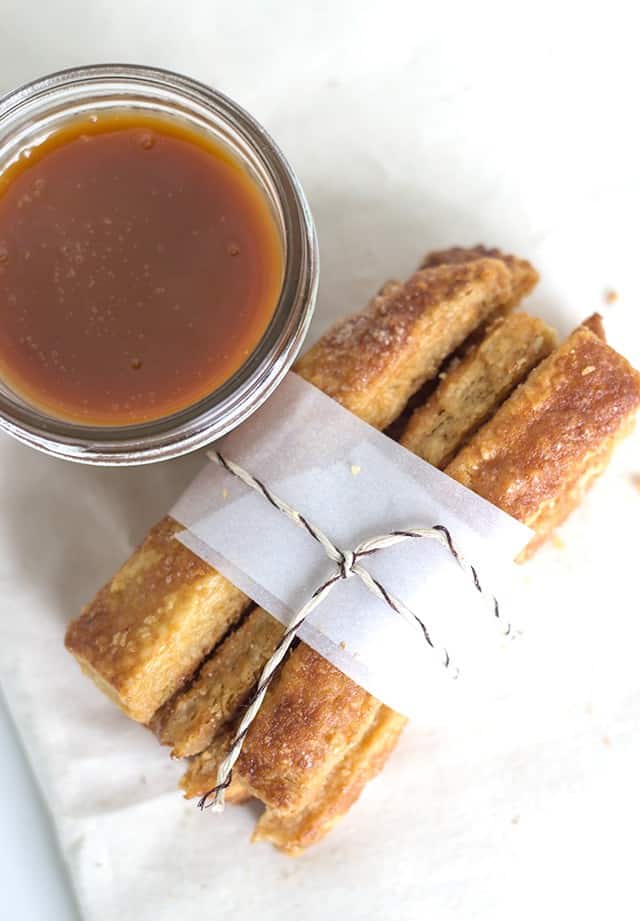 Cinnamon sticks with a flaky pie dipping sauce on a napkin.