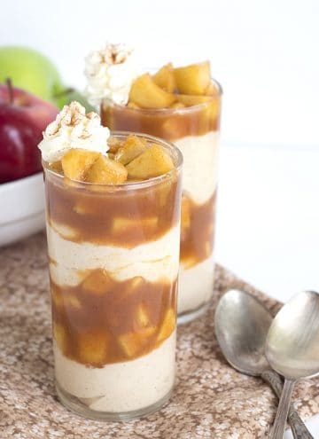 Caramel Apple Pie Cheesecake Parfaits - Caramel apple pie filling packed in a cup with warm cinnamon cheesecake filling and served with a swirl of whipped cream and dash of cinnamon