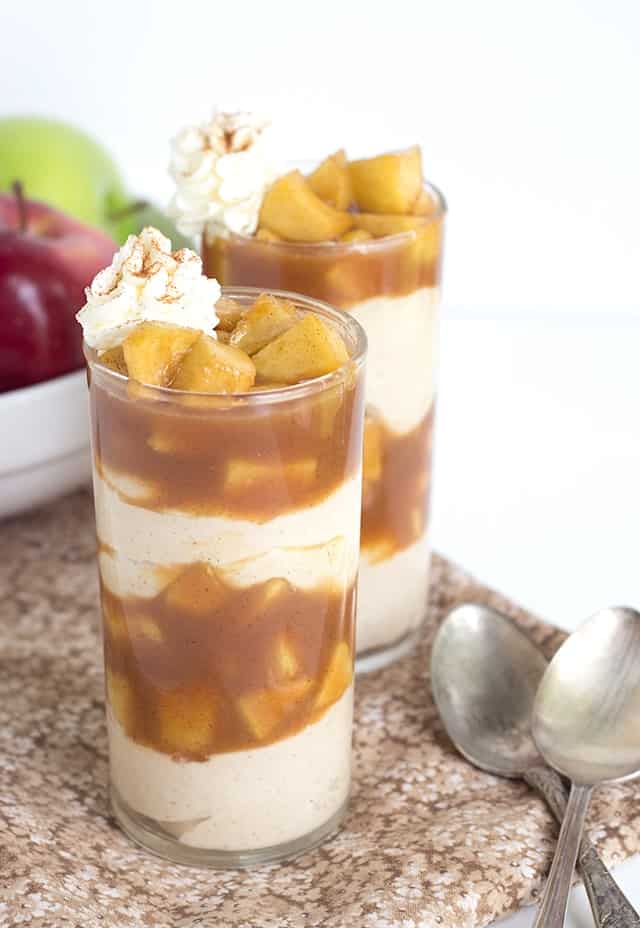 Caramel Apple Pie Cheesecake Parfaits - Caramel apple pie filling packed in a cup with warm cinnamon cheesecake filling and served with a swirl of whipped cream and dash of cinnamon