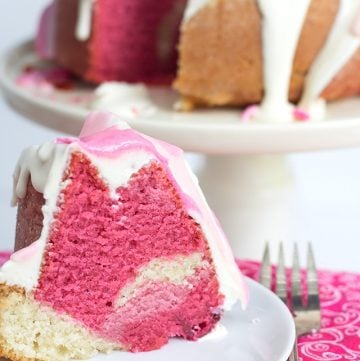 A Raspberry Vanilla Pink Ombre Bundt Cake with a slice taken out.