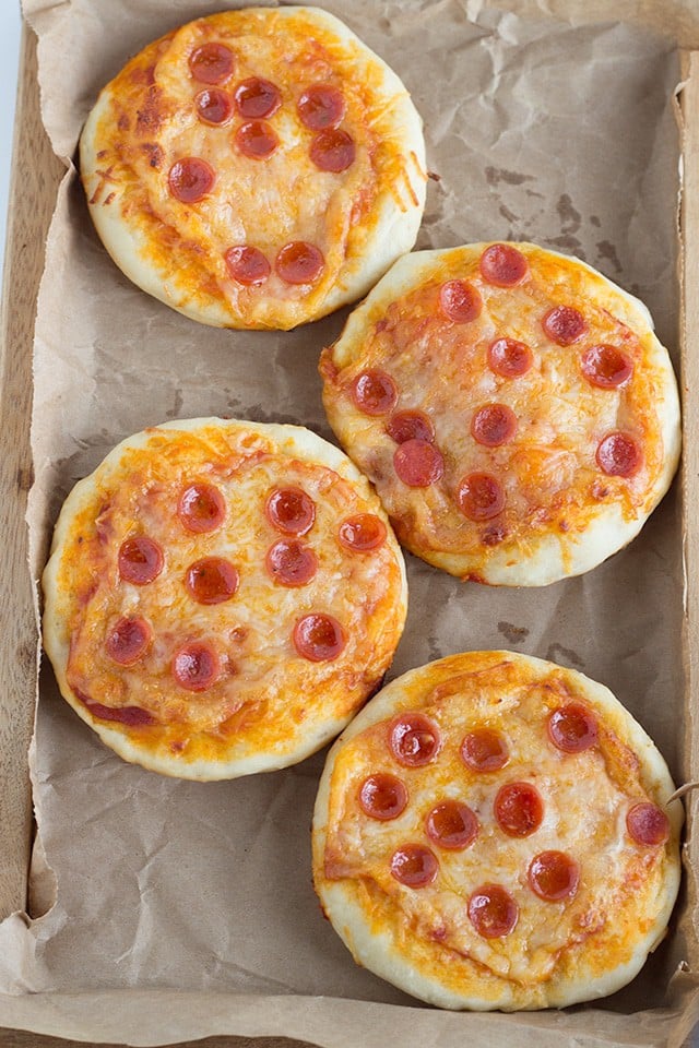 4 Mini pepperoni pizzas on a wooden tray