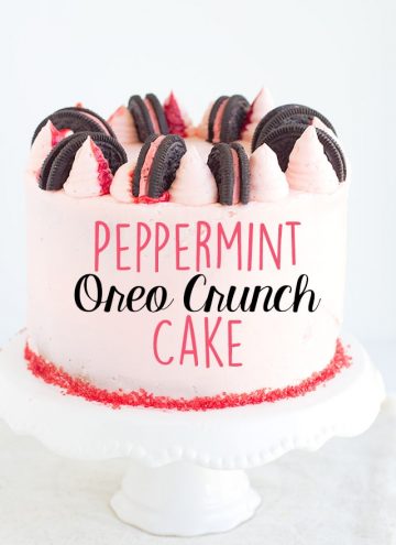 Showing whole peppermint oreo crunch cake on white cake plate with text on photo