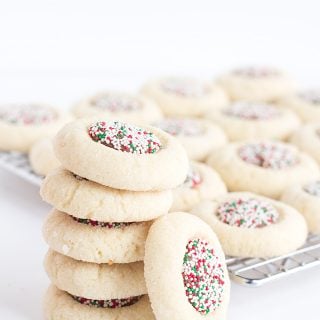 A stack of candy thumbprint cookies with sprinkles on top.