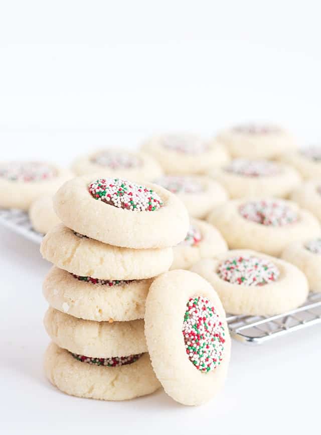 A stack of candy thumbprint cookies with sprinkles on top.