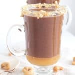 Two mugs filled with hot cocoa and cashews.