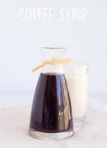 carafe of homemade coffee syrup with a glass of milk behind it