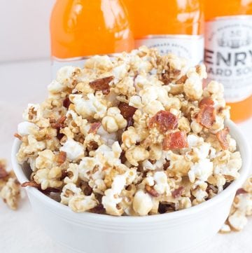 A bowl of maple bacon popcorn with soda bottles.