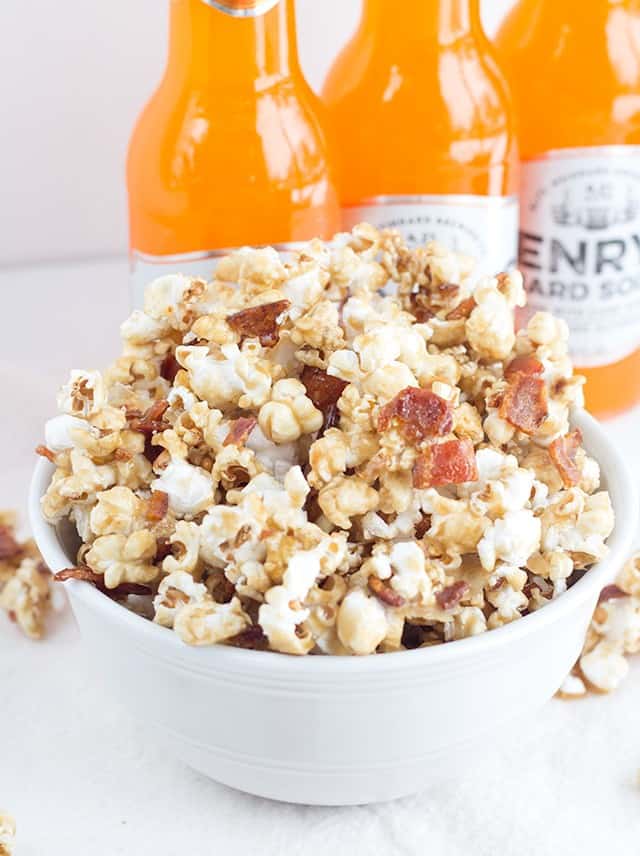 A bowl of maple bacon popcorn with soda bottles.