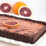 Blood orange tart on a white plate served with chocolate.