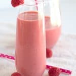 A pink smoothie with raspberries.