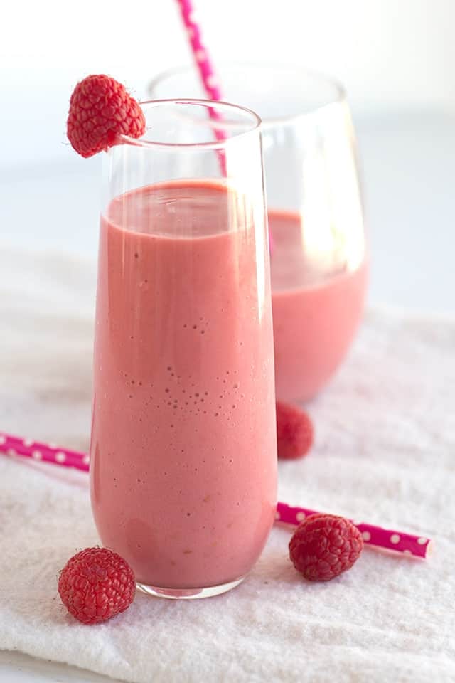 A pink smoothie with raspberries.