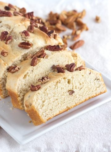 two slices of 4 ingredient ice cream bread on a white plate with pecans