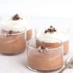 Four Baileys chocolate mousse cups with whipped cream and a spoon.