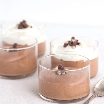 Four Baileys chocolate mousse cups with whipped cream and a spoon.