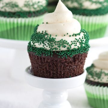 Guinness cupcakes topped with cream cheese frosting and green sprinkles for St Patrick's Day.