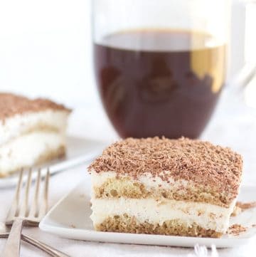 A slice of Easy Tiramisu cake on a plate with a cup of coffee.