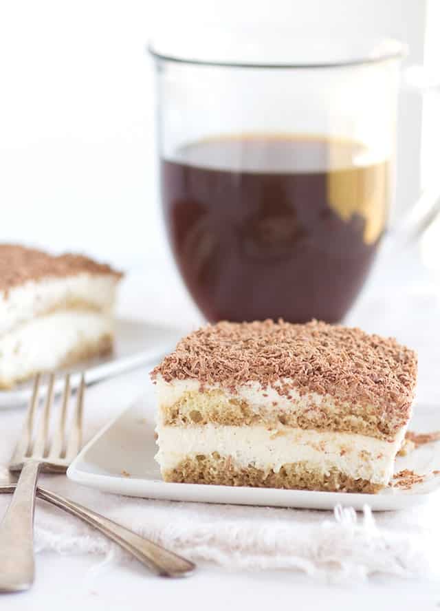 Plate of Tiramisu next to a mug of coffee