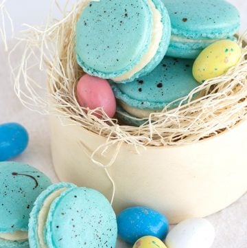 Malted milk French macarons in an Easter nest with easter eggs.
