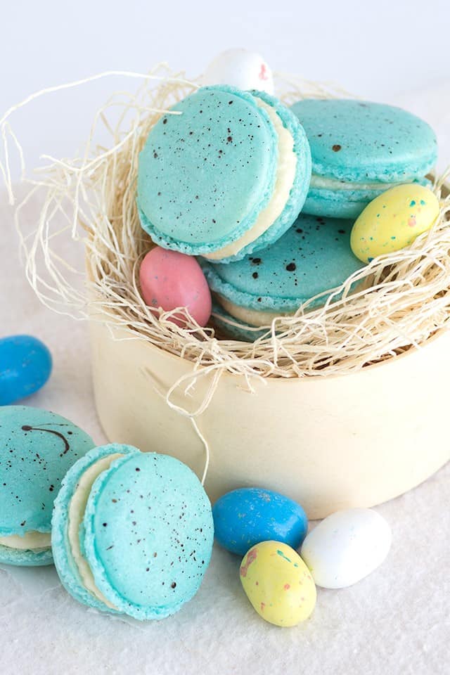 Malted milk French macarons in an Easter nest with easter eggs.
