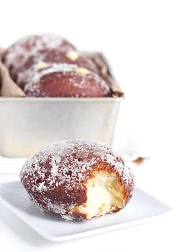 Vanilla cream-filled donuts covered in powdered sugar on a plate.