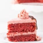 A slice of fresh red velvet cake on a white plate.