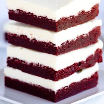 A stack of chewy red velvet bars on a white plate.