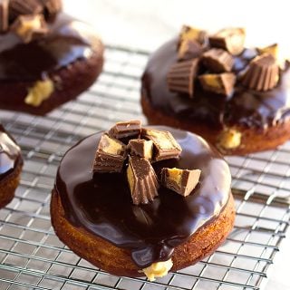 Chocolate glazed donuts with peanut butter filling arranged on a cooling rack.