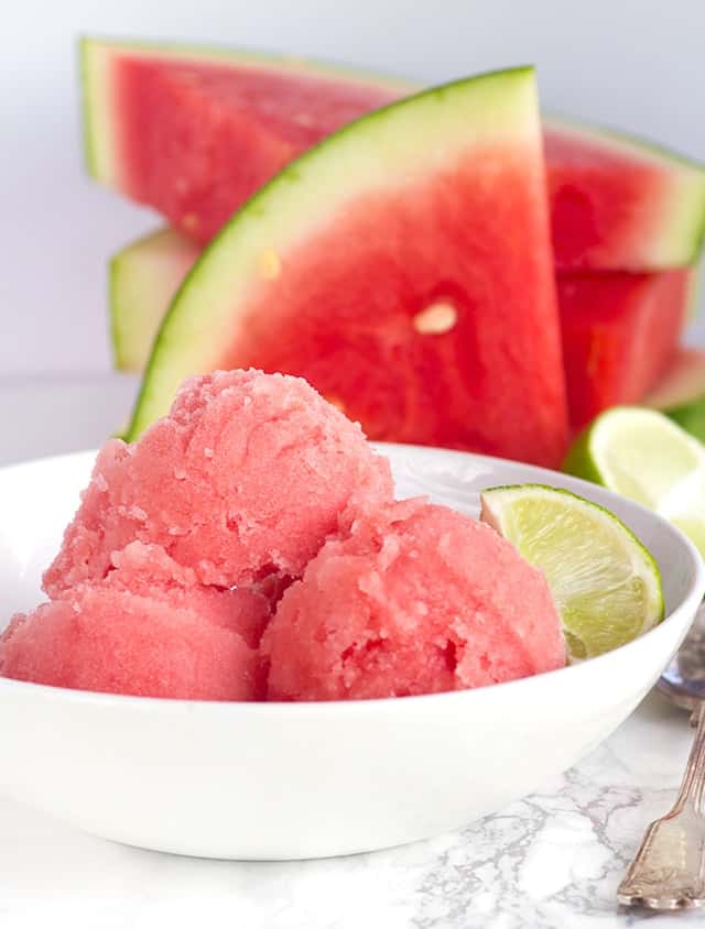 3 scoops of Watermelon Sorbet in a bowl next to slices of fresh watermelon