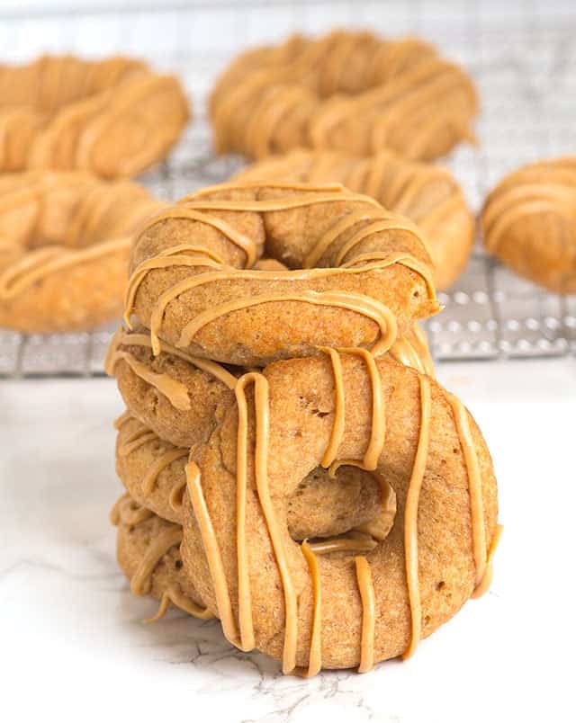 stack of dog donuts on a marbled surface with a wire rack behind the stack