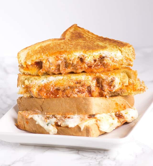 A stack of grilled cheese sandwiches, resembling a layered lasagna, on a white plate.
