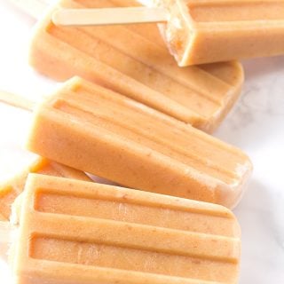 Peaches and cream ice pops on a marble countertop.