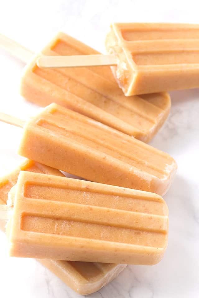 Peaches and cream ice pops on a marble countertop.