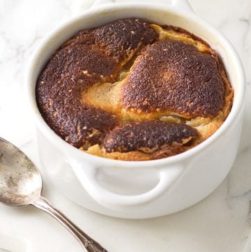 A white dish with a spoon in it containing peanut butter molten lava cakes.