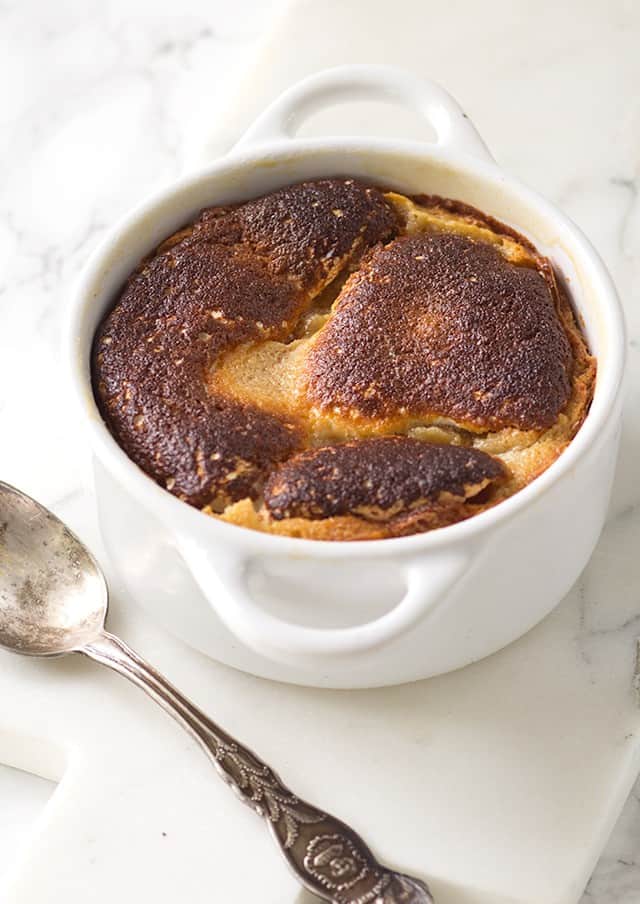 A white dish with a spoon in it containing peanut butter molten lava cakes.