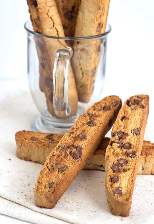 Chocolate chip biscotti on a napkin next to a glass.