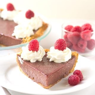 A decadent slice of chocolate pie topped with whipped cream and raspberries.