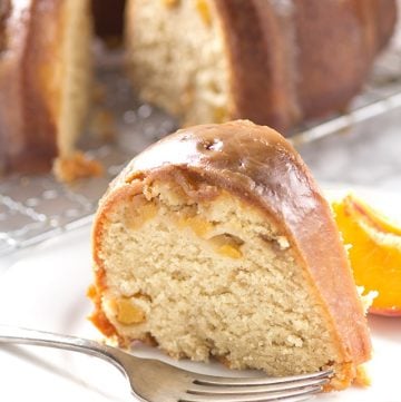 A luscious slice of homemade pound cake made with juicy peaches, delicately arranged on a plate.