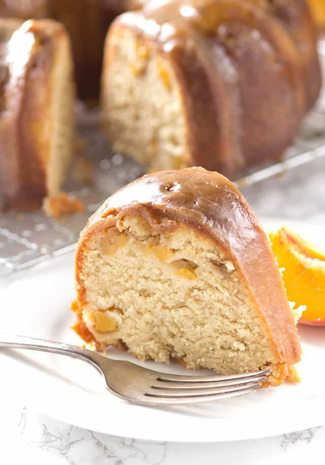 A luscious slice of homemade pound cake made with juicy peaches, delicately arranged on a plate.