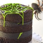 A Spider Egg Brownie Cake with green frosting and spiders on top.
