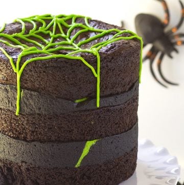 A Spider Egg Brownie Cake with green frosting and spiders on top.