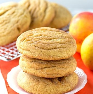 A stack of Apple Pie Stuffed Snickerdoodles with peaches in the background.