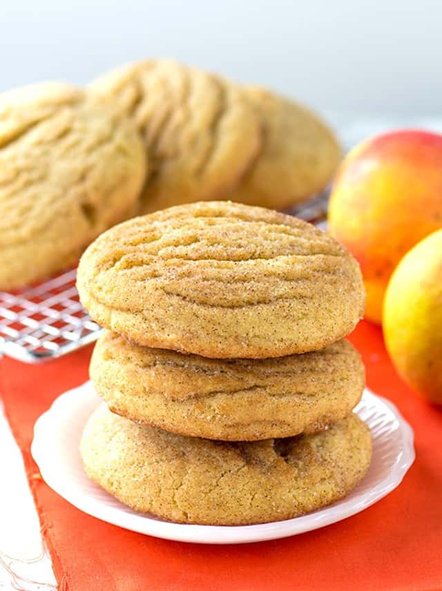 A stack of Apple Pie Stuffed Snickerdoodles with peaches in the background.