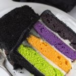 A Halloween-inspired slice of black and purple cake on a plate.