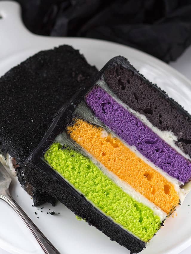 A Halloween-inspired slice of black and purple cake on a plate.