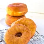 Three potato donuts sitting on a cooling rack.