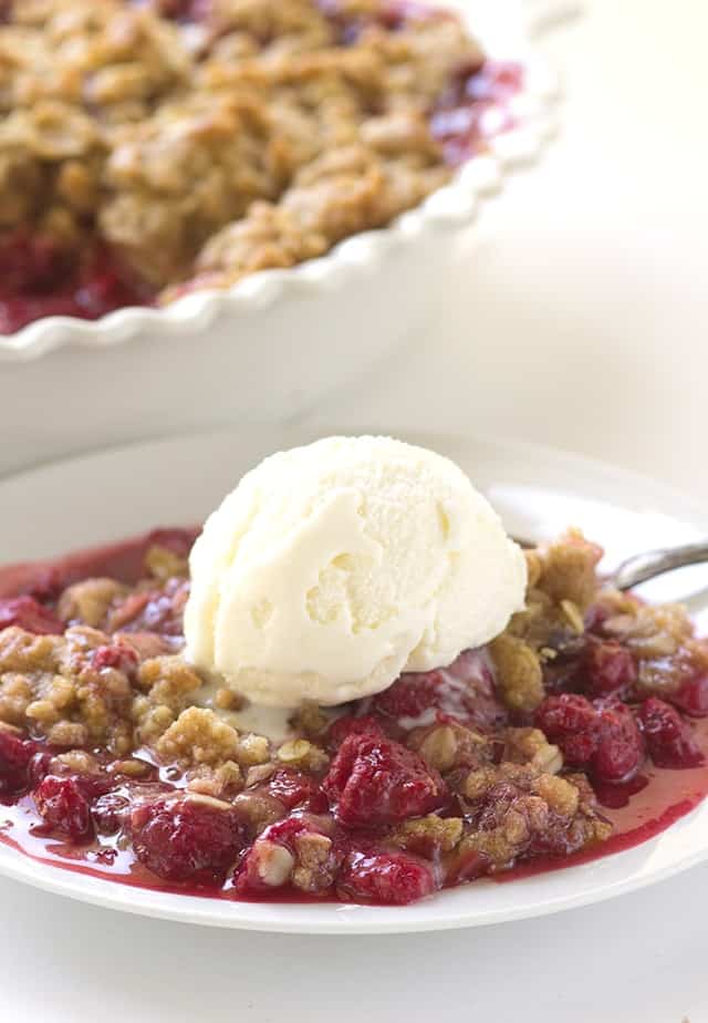 A plate of raspberry crisp with ice cream.