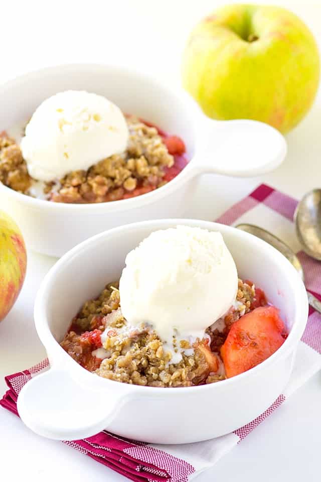 Two bowls of Crock Pot apple crisp with ice cream and apples.