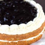 A cake with blueberries and cream on top, resembling a Cherry Torte.